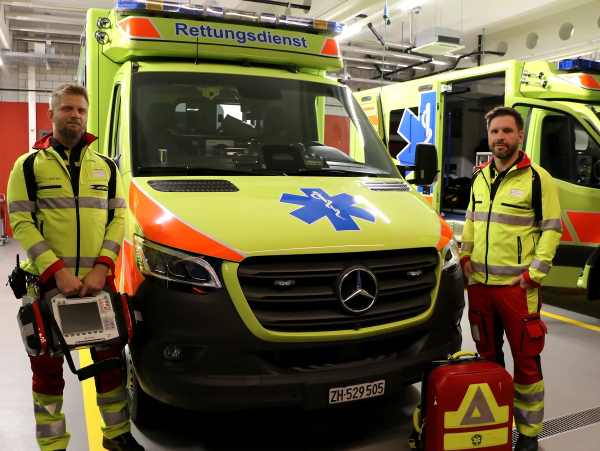 Zwei Rettungssanitäter des Rettungsdiensts des Spitals Uster vor einem Rettungswagen.  
